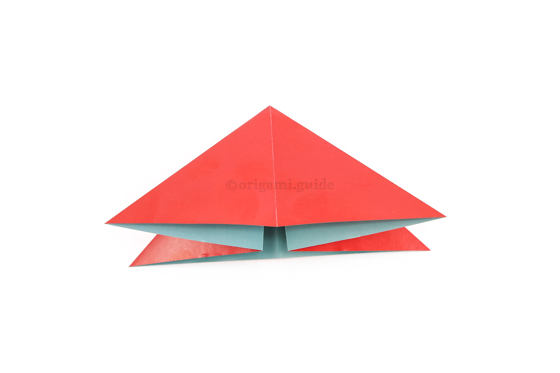 Flatten the paper into a triangular shape.