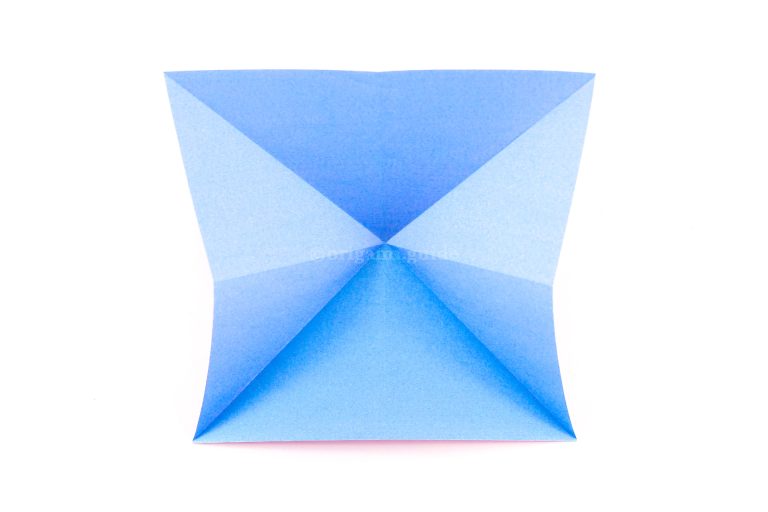 Bring the left and right sides forward and down, collapsing the paper into a triangular shape.