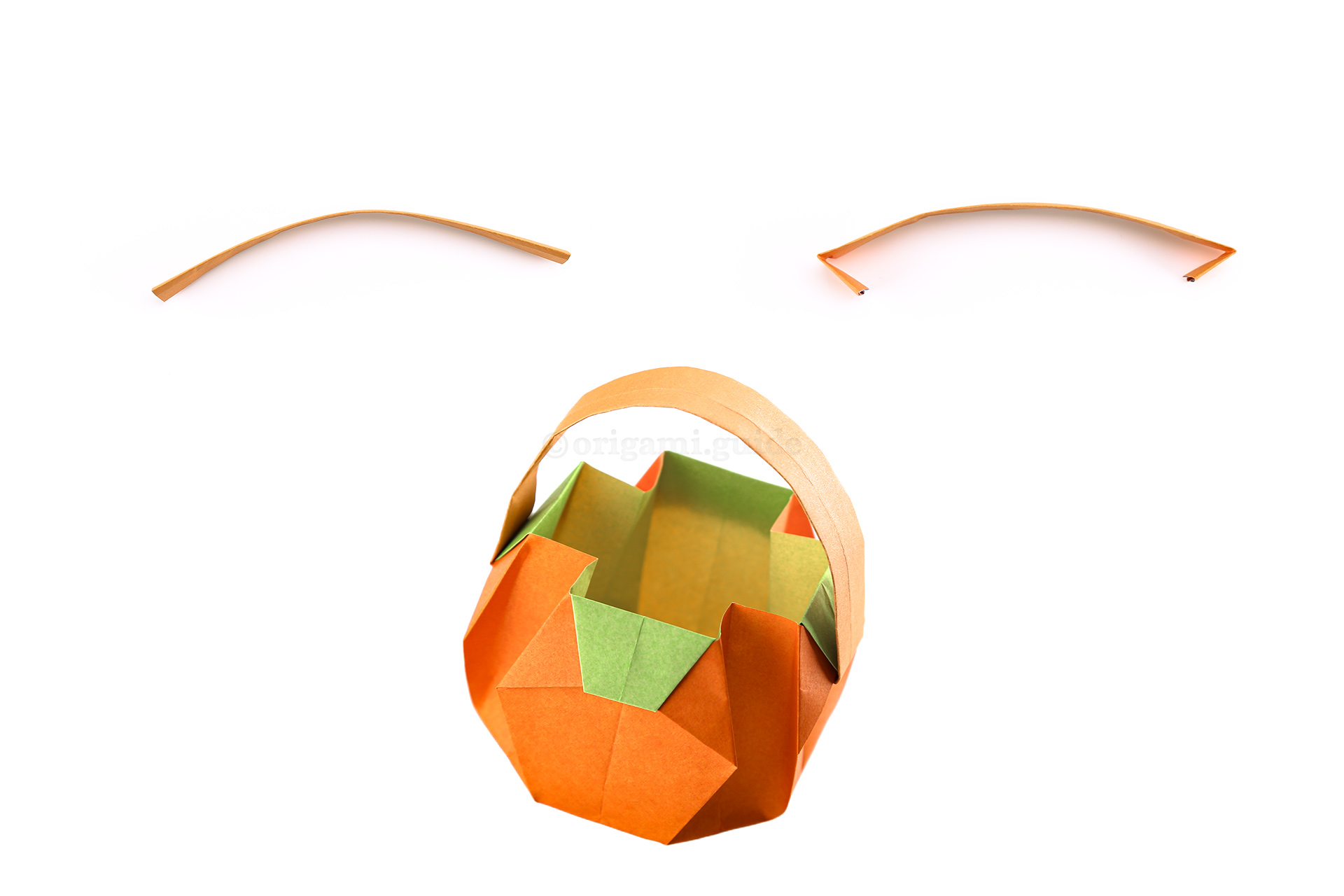 Step 43 - Now you can curve the paper handle, and fold over the ends to create two hooks.
Use some glue on the ends and slot them into two opposite flaps on the origami pumpkin.
